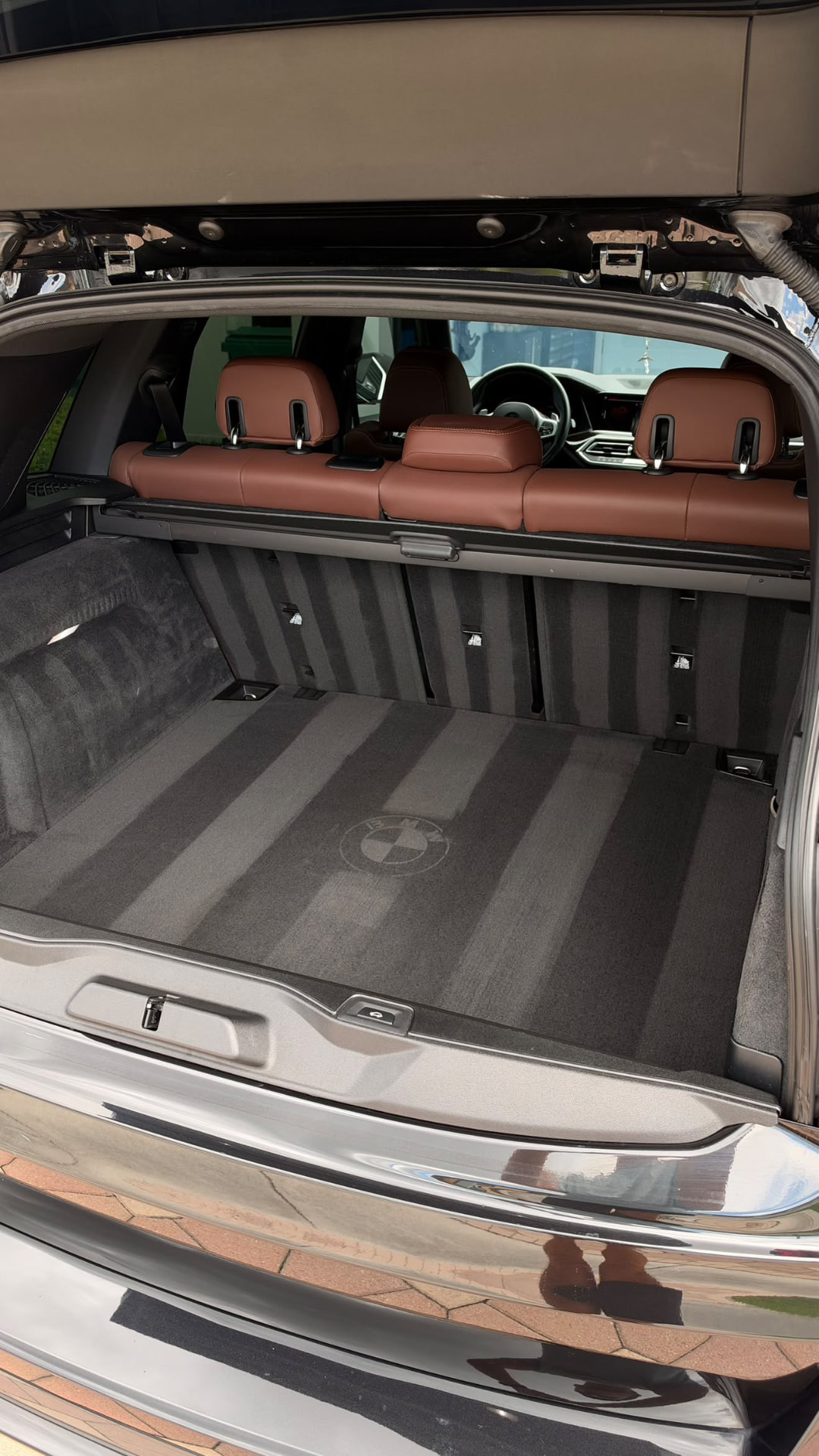 BMW X5 cargo area with clean striped carpeting and brown leather seats